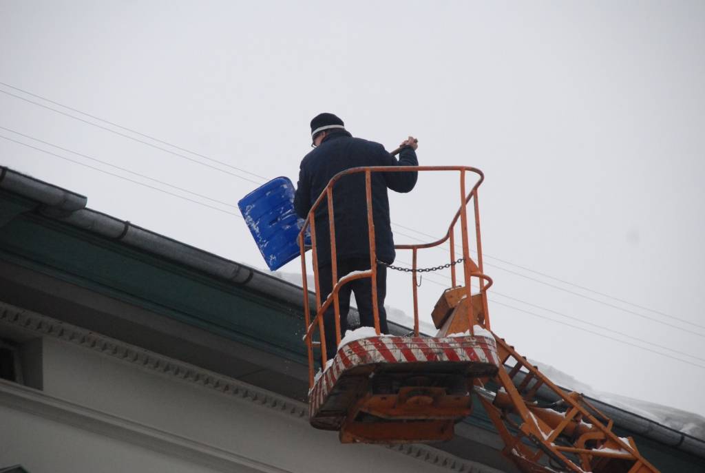 Valsts Nekustamo īpašumu aģentūra no apsaimniekojamo namu jumtiem Tirgoņu ielā novāc sniegu, kas bīstami pārkāries pāri jumta malai.
