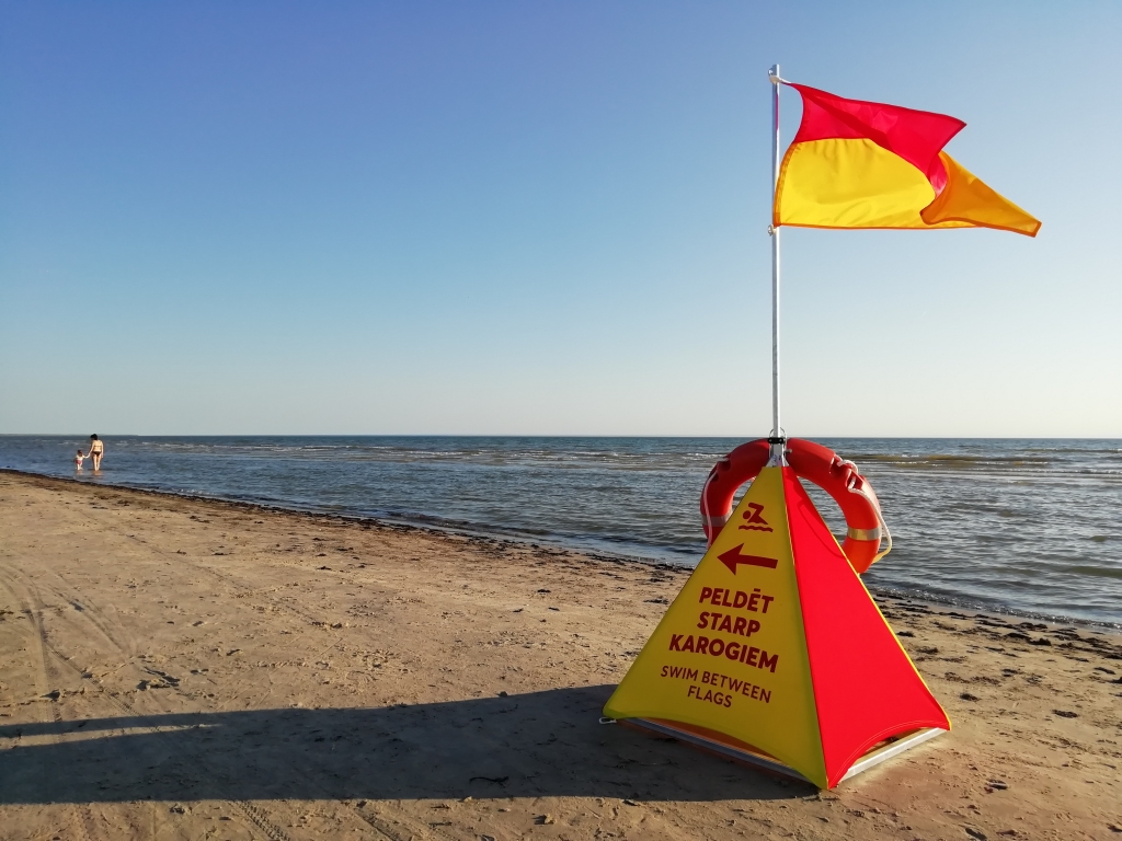Peldvietu zonas, kurās peldēties drošāk, šovasar ik dienas, kad piemēroti laika apstākļi,  glābēji apzīmē ar šādiem karodziņiem un uzrakstu “Peldēt starp karogiem”.
Autors: Aigars Štāls